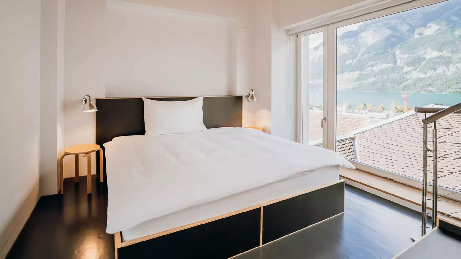 Ein schwarzes Bett in der Loftsuite Turmloft des Lofthotels Murg mit Aufsicht auf den Walensee und die Churfirsten.